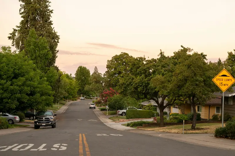 Single-story Sacramento homes set behind lawns along a street shaded by large old trees